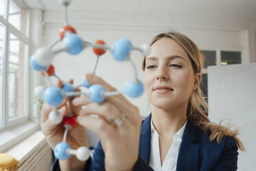 Beautiful businesswoman analyzing molecular model in office - JOSEF10097