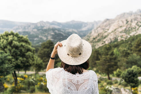 Woman wearing hat looking at mountain - DAMF00951