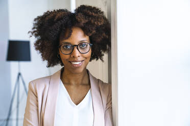 Smiling woman wearing blazer standing by wall - VPIF06184