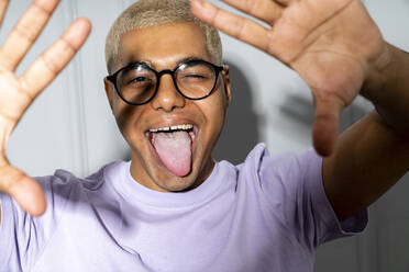 Young man wearing eyeglasses sticking out tongue - VPIF06237