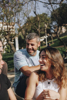 Glückliche Freunde unterhalten sich im Park an einem sonnigen Tag - MRRF02139