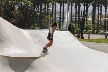 Frau fährt Skateboard auf einer Sportrampe - MRRF02150