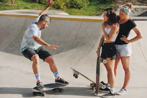 Mann auf dem Skateboard vor Freunden auf einer Sportrampe an einem sonnigen Tag - MRRF02157