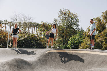 Skateboarders holding skateboards on sports ramp - MRRF02173