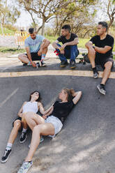 Friends taking break and relaxing at skateboard park - MRRF02177