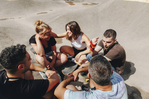 Fröhliche Freunde unterhalten sich im Skateboardpark an einem sonnigen Tag - MRRF02187