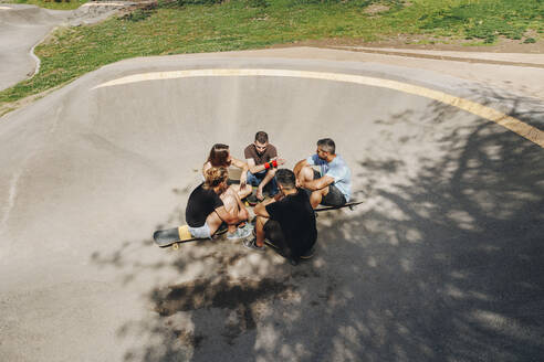 Freunde sitzen auf der Rampe und unterhalten sich im Skateboard-Park - MRRF02188