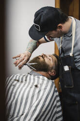 Barbier trimmt den Bart eines Kunden im Salon - JUBF00425