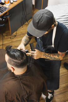 Hairstylist cutting hair for customer in salon - JUBF00427