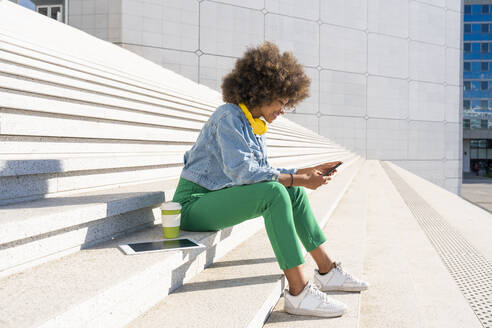 Lächelnde Frau mit Smartphone, sitzend mit Tablet-PC und Einwegbecher auf Stufen - OIPF01791