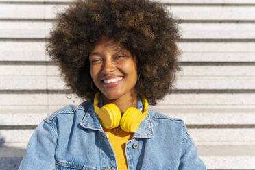 Glückliche schöne Afro-Frau mit drahtlosen Kopfhörern auf Stufen - OIPF01803