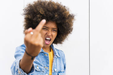 Afro woman showing finger in front of wall - OIPF01817