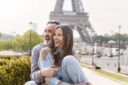 Fröhliches reifes Paar sitzt zusammen vor dem Eiffelturm, Paris, Frankreich - OIPF01839