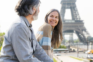Glückliche reife Frau, die einen Mann ansieht, der vor dem Eiffelturm sitzt, Paris, Frankreich - OIPF01844