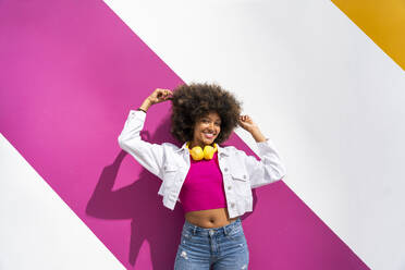 Lächelnde Afro-Frau mit Haaren vor weißer und rosa Wand - OIPF01868