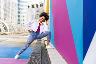 Smiling young Afro woman by colorful wall - OIPF01895