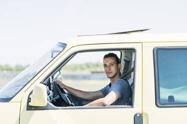 Hübscher junger Mann sitzt im Van an einem sonnigen Tag - DAMF00970