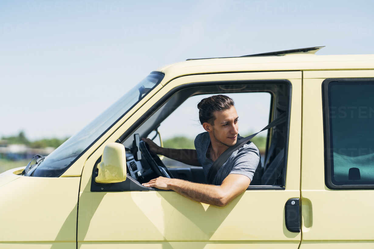 Junger Mann im Auto, der aus dem Fenster schaut, lizenzfreies Stockfoto