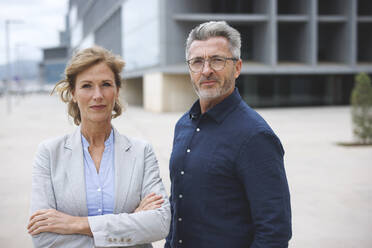 Businesswoman with arms crossed standing by businessman wearing eyeglasses - JOSEF10112