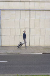 Geschäftsmann mit Koffer auf dem Fußweg an der Mauer - JOSEF10197