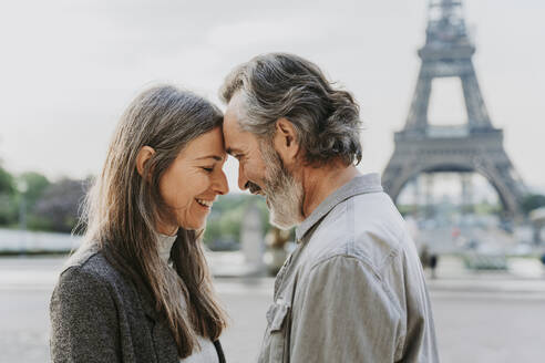 Happy mature couple touching foreheads in front of Eiffel Tower, Paris, France - OIPF01906