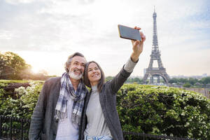 Glückliche Frau, die ein Selfie mit einem Mann durch ein Smartphone vor dem Eiffelturm macht, Paris, Frankreich - OIPF01911