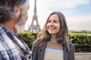 Lächelnde reife Frau, die einen Mann vor dem Eiffelturm ansieht, Paris, Frankreich - OIPF01913