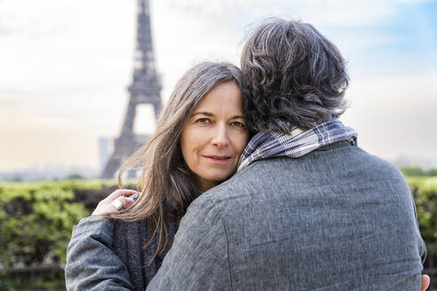 Lächelnde reife Frau, die einen Mann vor dem Eiffelturm umarmt, Paris, Frankreich - OIPF01915