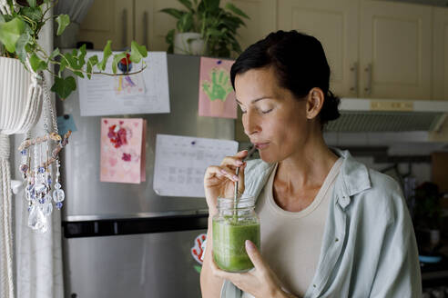 Woman drinking healthy smoothie from straw at home - TYF00187