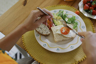 Hands of woman holding cutlery over plate at table - TYF00192