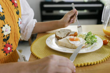 Hands of woman holding table knife and fork by plate on table - TYF00193