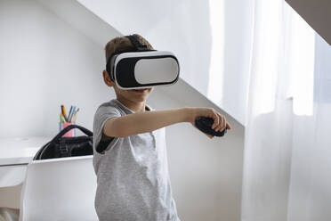 Junge mit VR-Brille spielt Videospiel zu Hause - MOMF00999