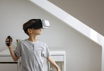 Junge mit Virtual-Reality-Simulator spielt Videospiel zu Hause - MOMF01000