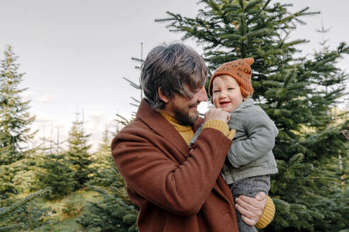 Happy father carrying son at Christmas tree farm - OGF01243