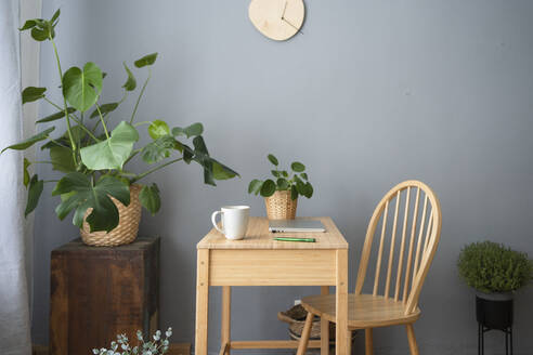 Coffee mug and laptop on desk in front of gray wall at home office - SVKF00210