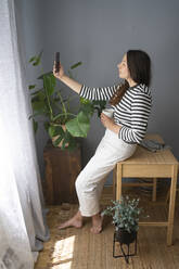 Frau hält Kaffeebecher und macht ein Selfie mit ihrem Smartphone im Büro zu Hause - SVKF00215