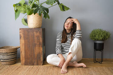 Contemplative woman with head in hands sitting on floor at home - SVKF00216