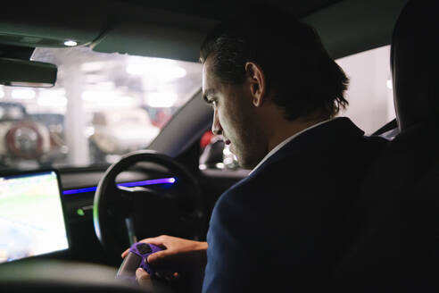 Geschäftsmann spielt mit Joystick im Elektroauto sitzend ein Spiel - ASGF02325