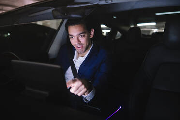 Geschäftsmann berührt GPS-Bildschirm in Elektroauto sitzend durch Windschutzscheibe gesehen - ASGF02327