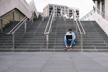 Mann mit Laptop auf einer Treppe sitzend - ASGF02338