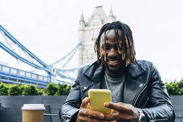 Smiling man text messaging on smart phone, London, England - ASGF02351