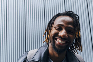 Happy man with dreadlocks in front of wall - ASGF02362