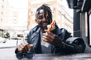 Happy man having ice cream at sidewalk cafe in city - ASGF02369