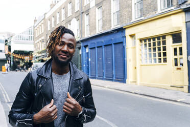 Young man in leather jacket standing on street - ASGF02380