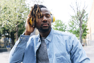 Young man listening music through wireless headphones - ASGF02381