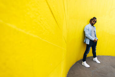 Junger Mann mit Sonnenbrille vor einer gelben Wand - ASGF02394