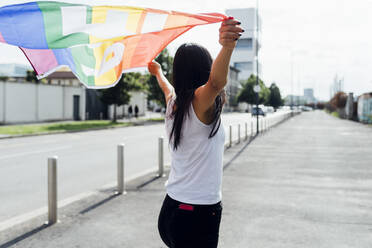 Young woman standing with rainbow flag on sunny day - MEUF05946