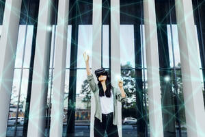 Frau erlebt VR-Simulation mit interaktiver Schnittstelle und zeigt begeistert ihre erhobene Hand - MEUF05978