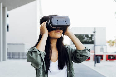 Young woman with black hair wearing virtual reality simulator - MEUF05984