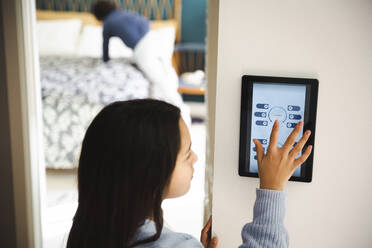 Girl touching screen of home automation device on wall at home - MASF30359